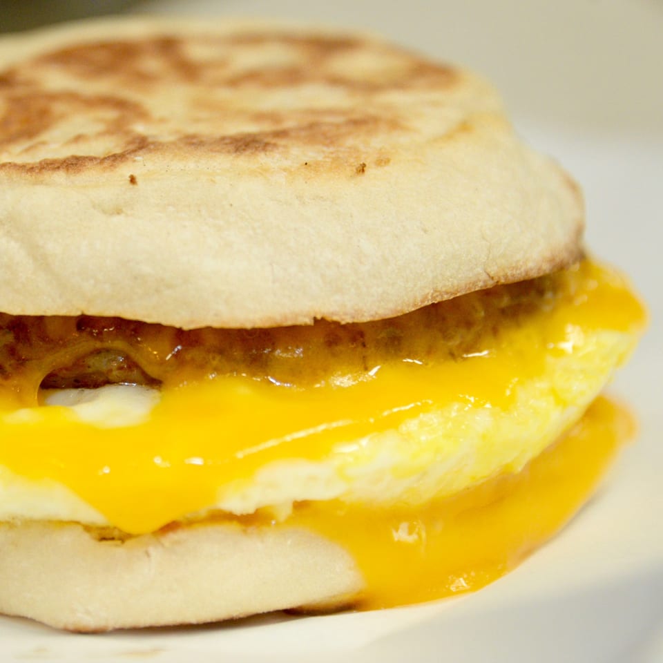 Close-up of a Sutter Street Cafe breakfast sandwich with egg, cheese, and sausage on an English muffin.